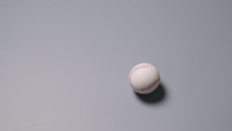 Draufsicht-Auf-Einen-Baseballball,-Der-Vor-Grauem-Hintergrund-über-Den-Rahmen-Rollt-1